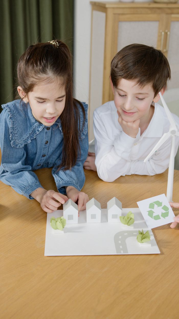 Kids explore renewable energy with a scale model featuring a wind turbine.